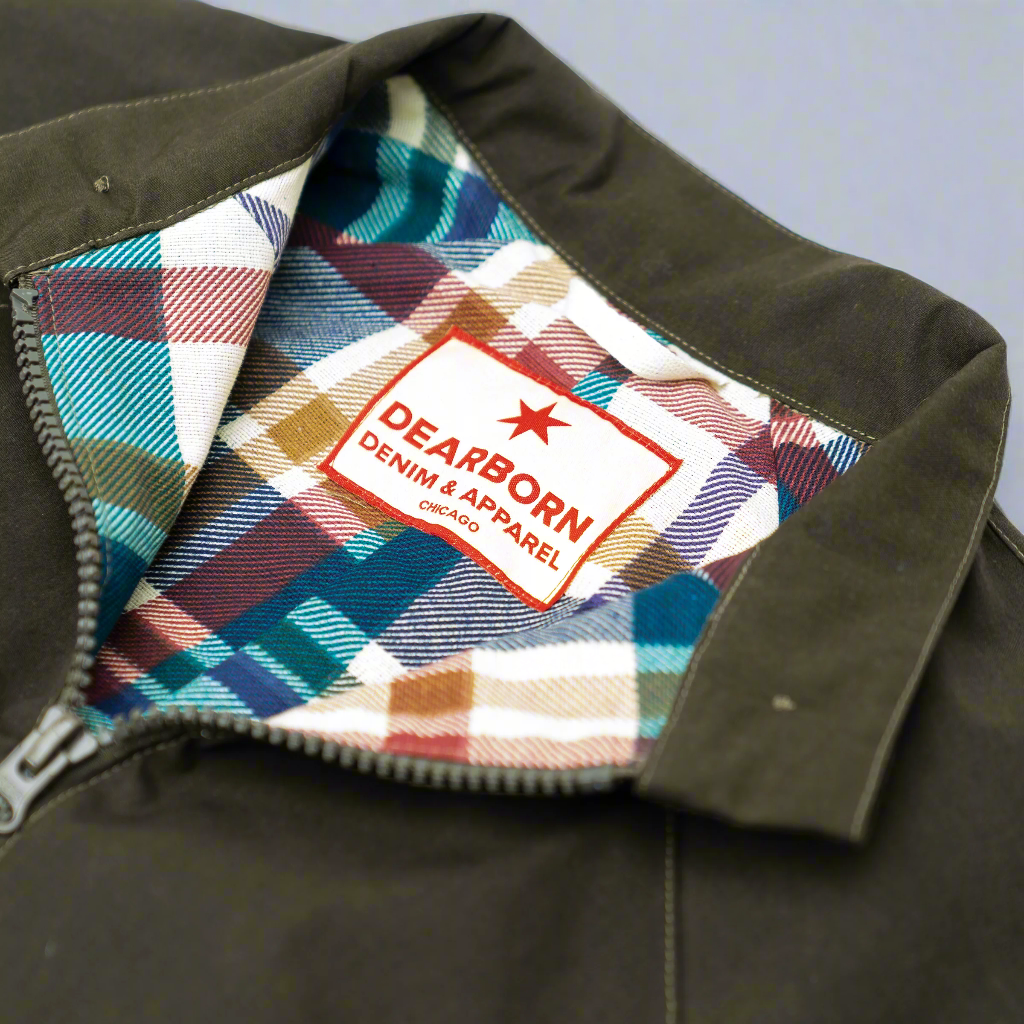 Model wearing the olive Harrington jacket open over a shirt, three-quarter view.