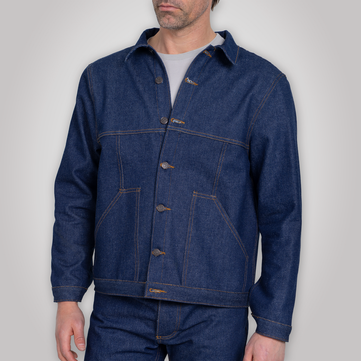 Close-up of the doughnut-style brass buttons and chest pocket on the denim jacket.