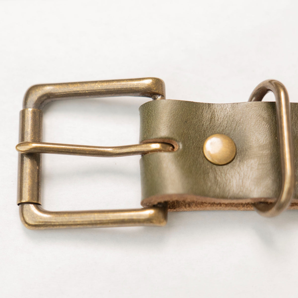 Close-up of the antique brass buckle and billet end of the olive Horween leather belt.