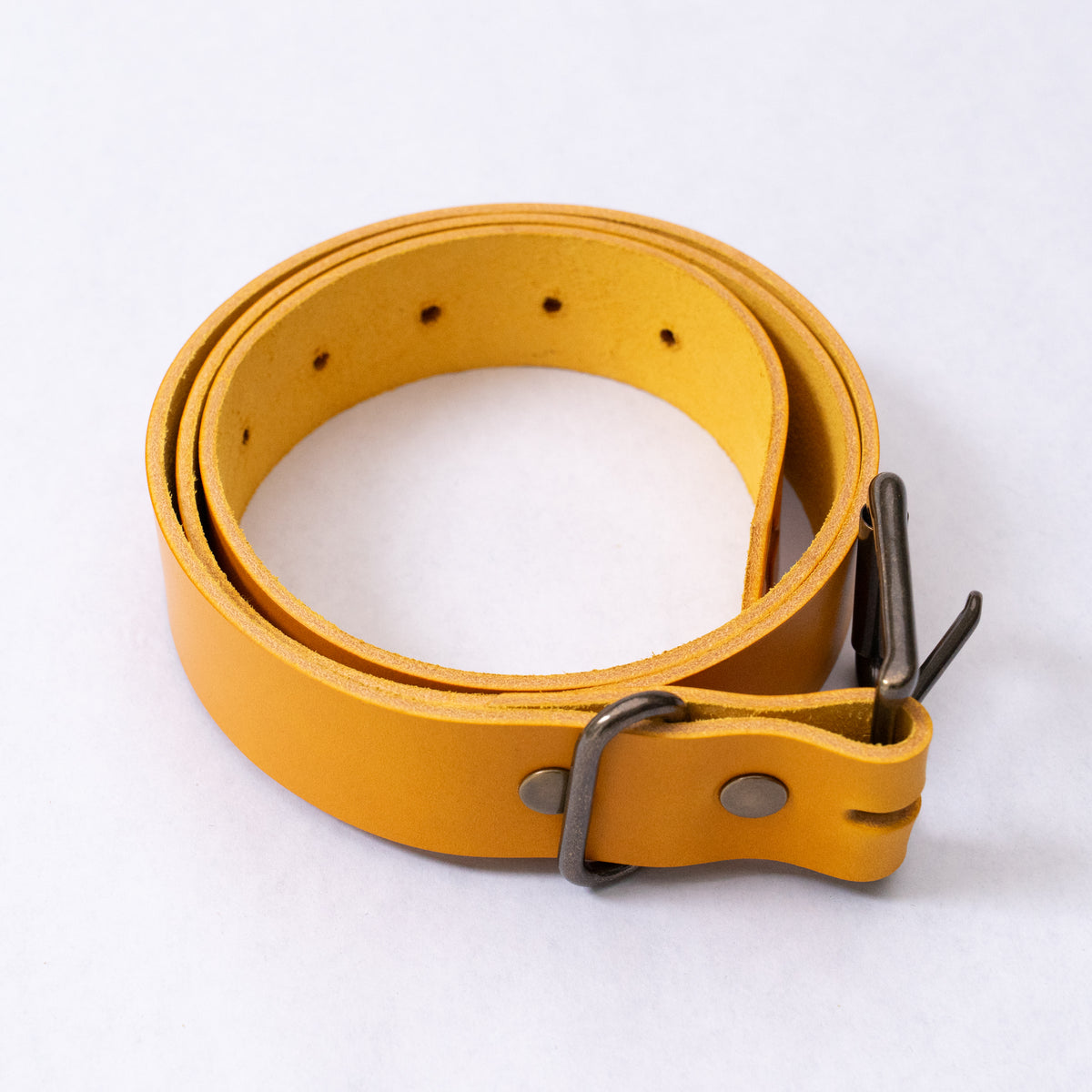 Close-up of the antique brass buckle and roller on the squash leather belt.