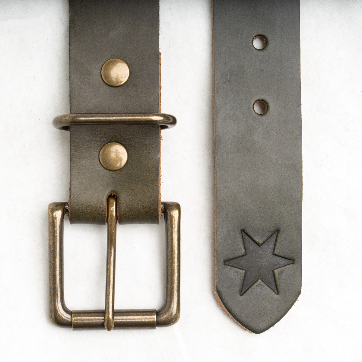 Olive bull hide leather belt coiled, showing solid brass buckle with antique brass finish.