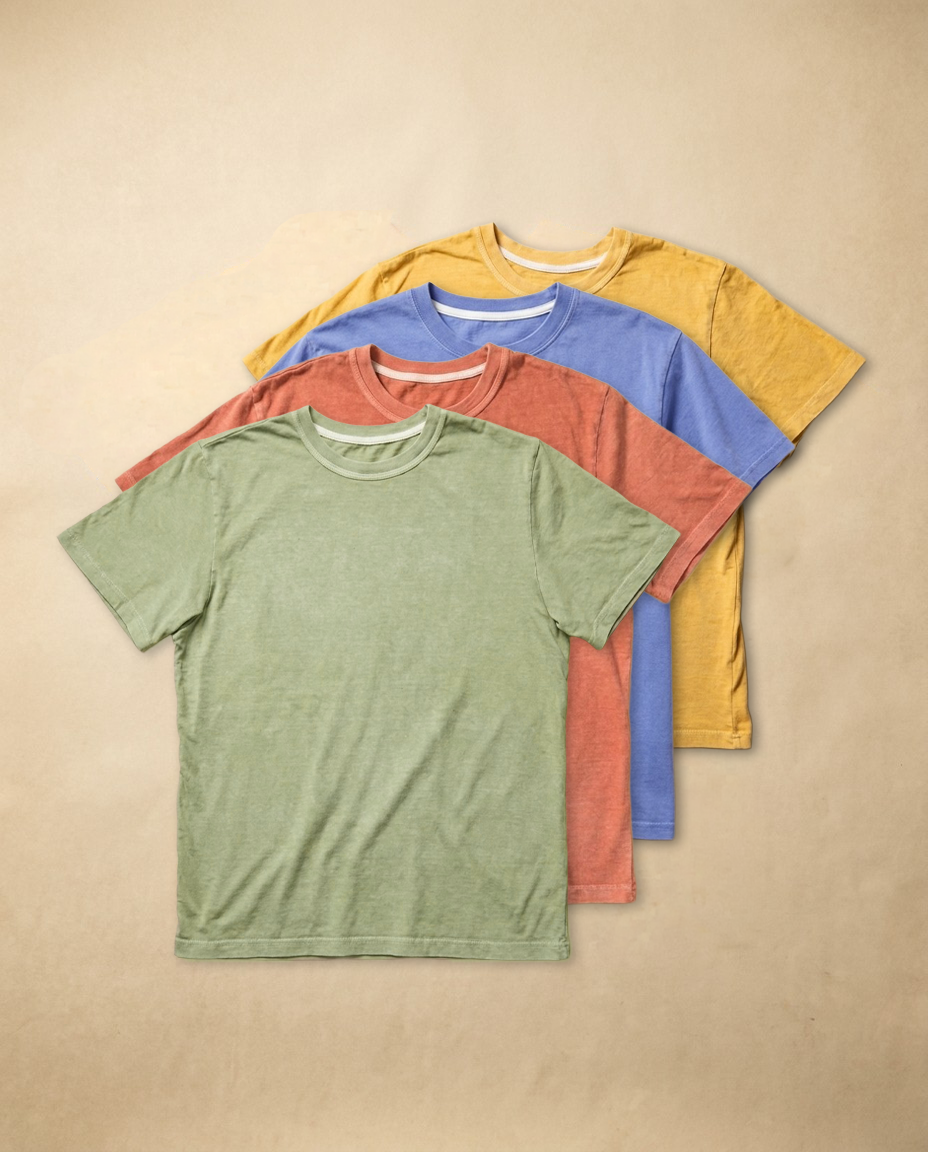 Four folded combed cotton t-shirts in assorted colors, stacked together as a four pack.