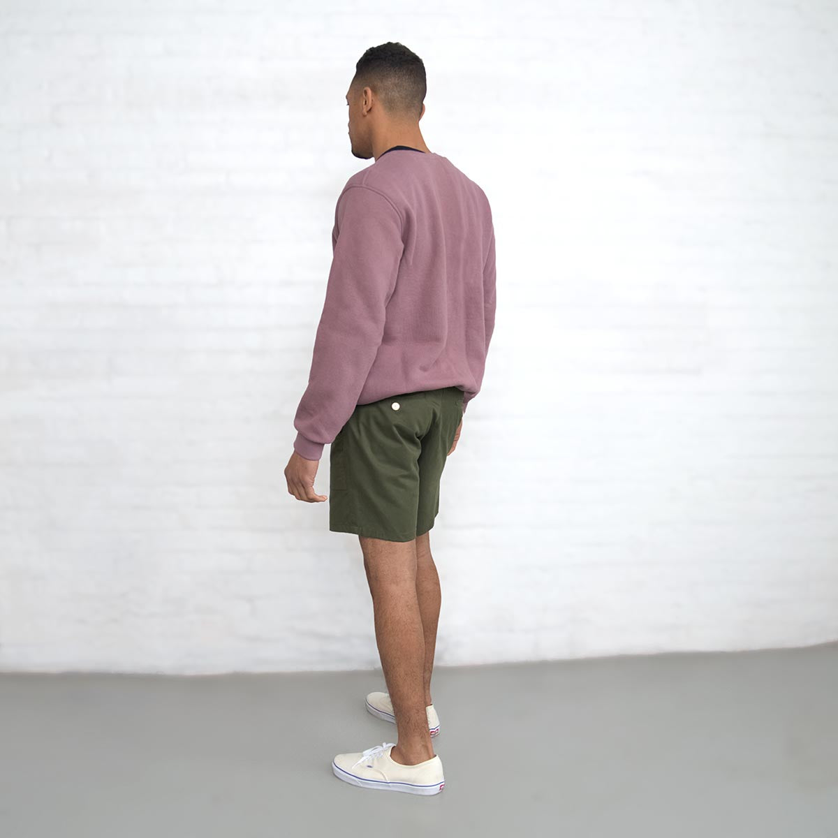 Side view of olive chino shorts on model showing medium rise and fit through the thigh.