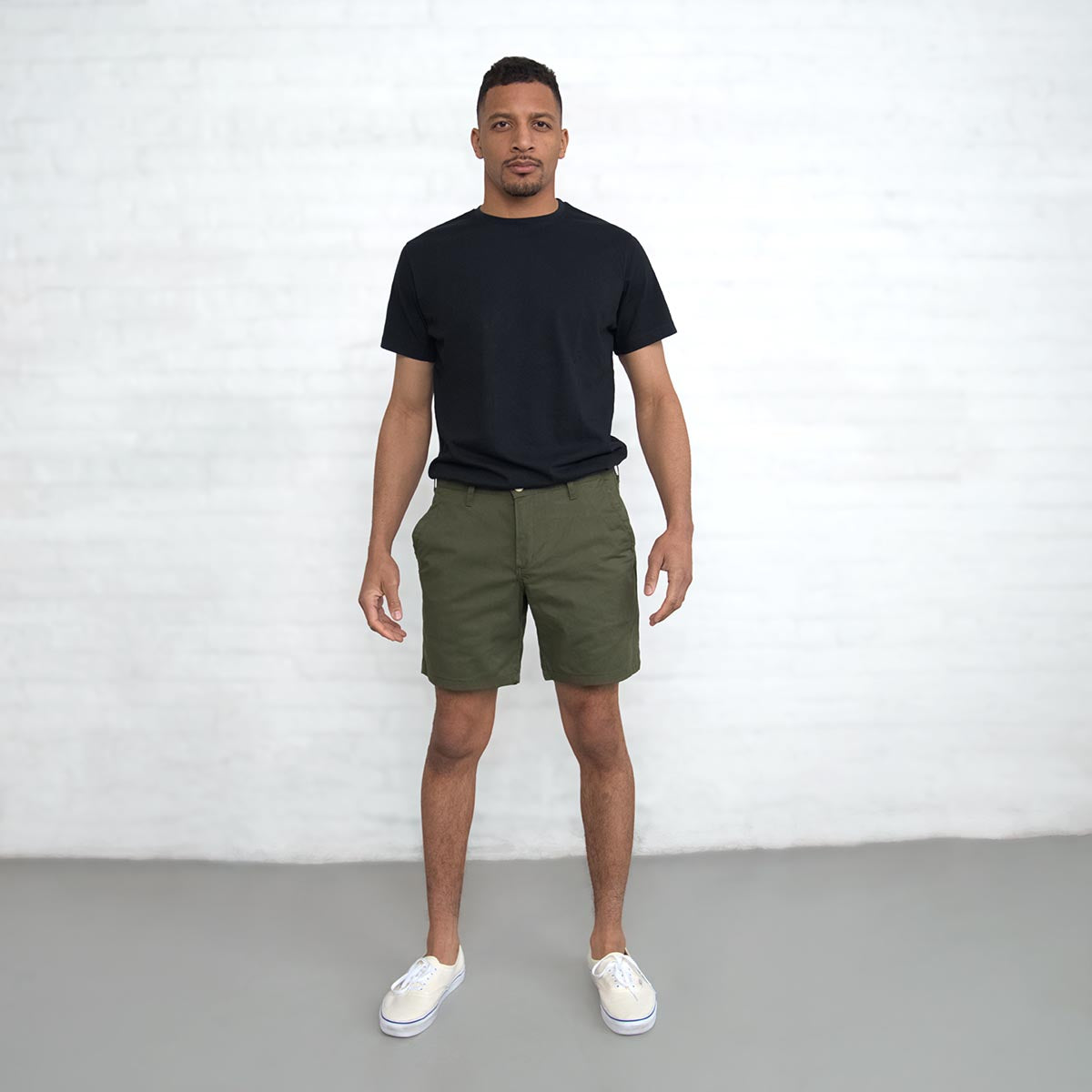 Man wearing olive chino shorts, front view from the waist down.