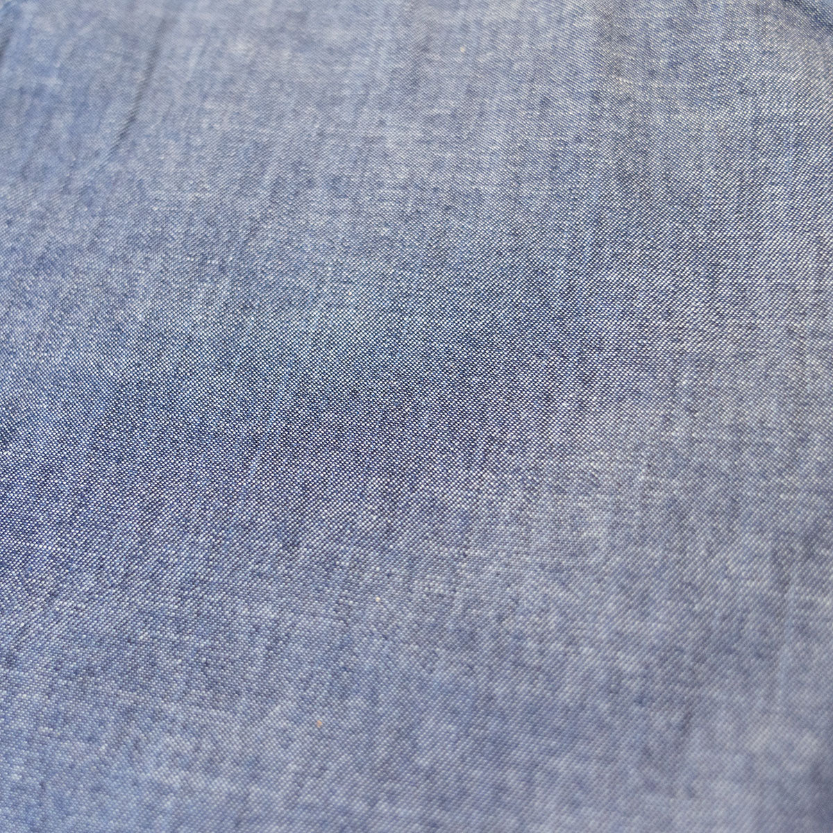 Detail of front pocket opening and stitching on light blue chambray shorts