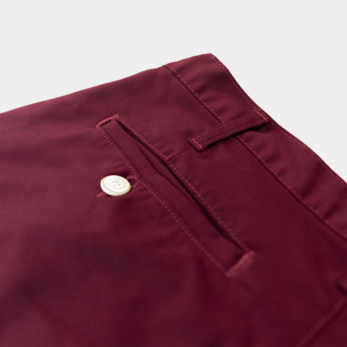 Close-up of the branded Italian button and YKK zipper fly on wine chinos
