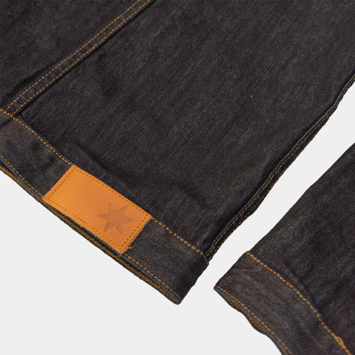 Chest pocket detail with yellow gold contrast thread on dark denim