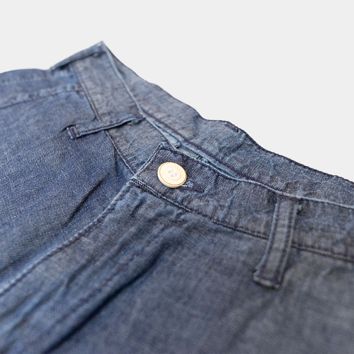 Close-up of chambray fabric weave and custom wood button on the waistband