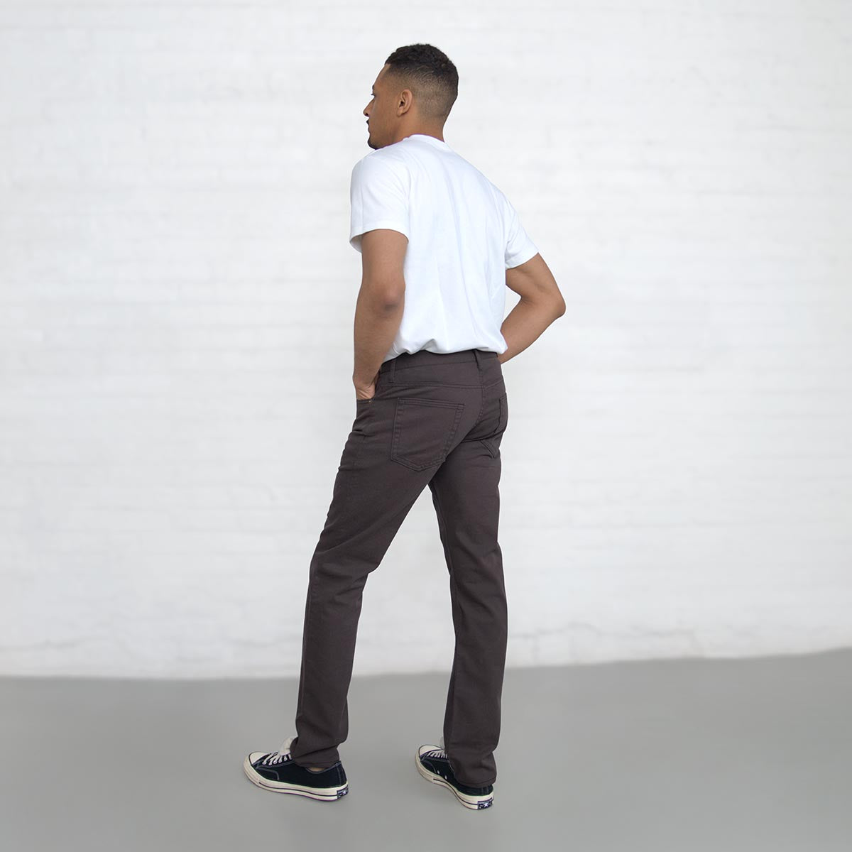 Waist-down shot of espresso jeans worn with a belt and tucked shirt.