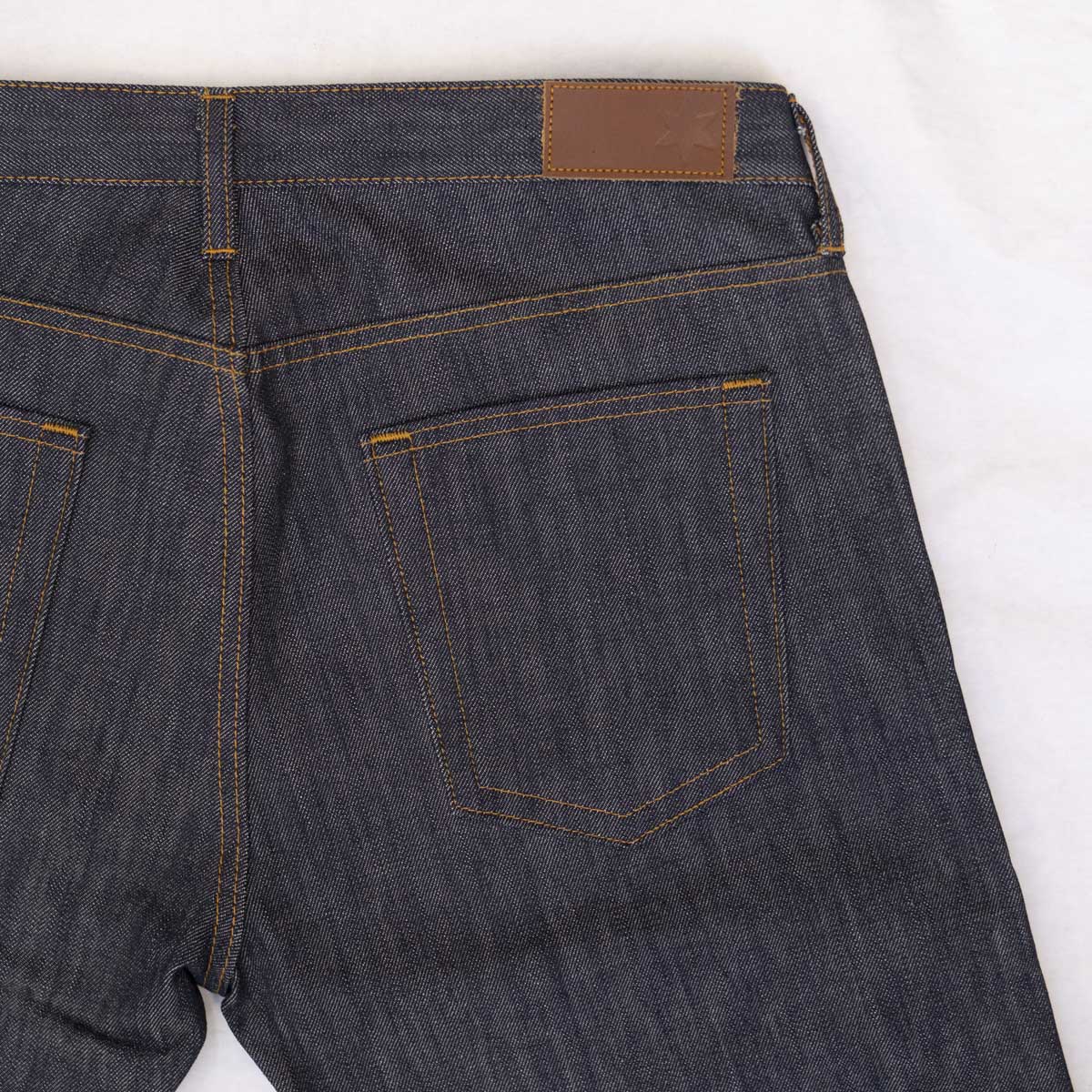 Detail of the front waistband with rivets, button and YKK zipper fly.
