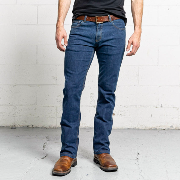 Boot cut men's jeans in a medium blue stone wash, shown front-on with a leather patch at the waistband.