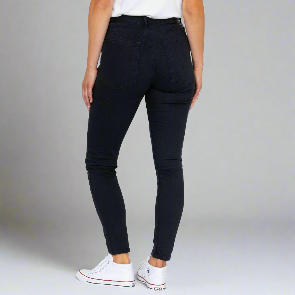 Close-up of black stretch denim showing the gold leaf button and YKK zipper fly.