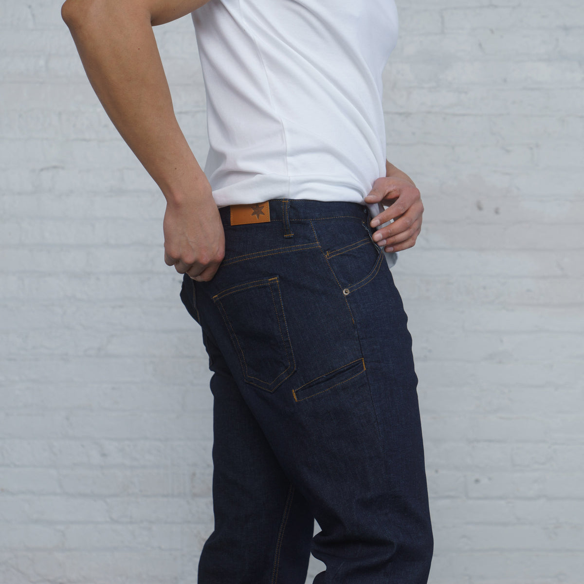 Man wearing relaxed fit dark wash jeans, full length back