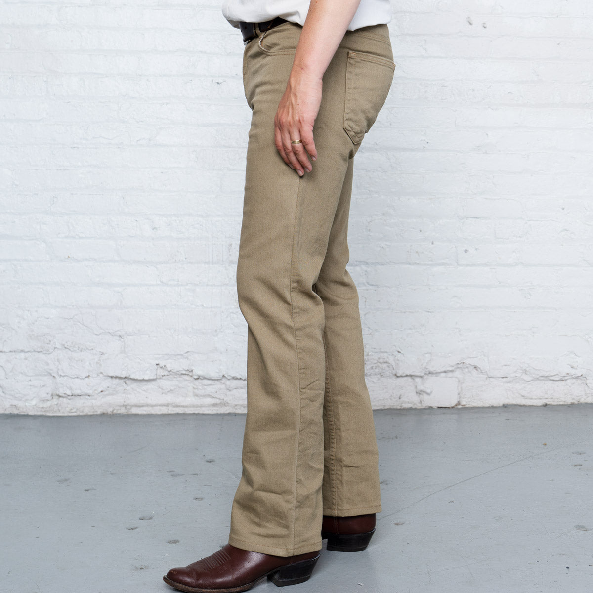 Man wearing khaki boot cut jeans, shown from the waist down at full length.