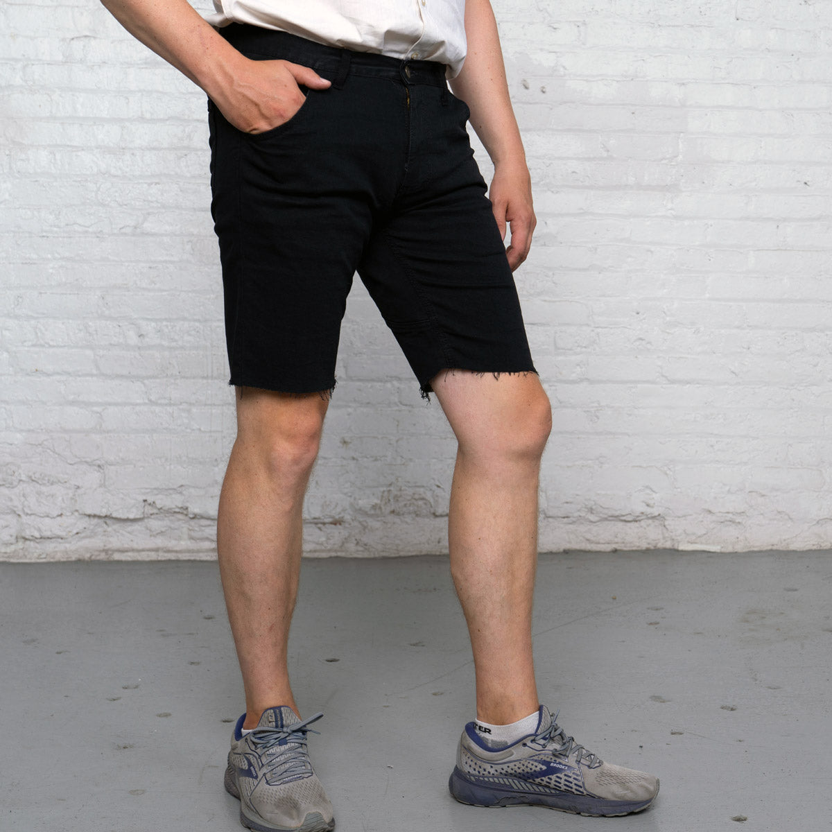Close-up of the raw edge hem on the leg opening of the black commuter shorts.