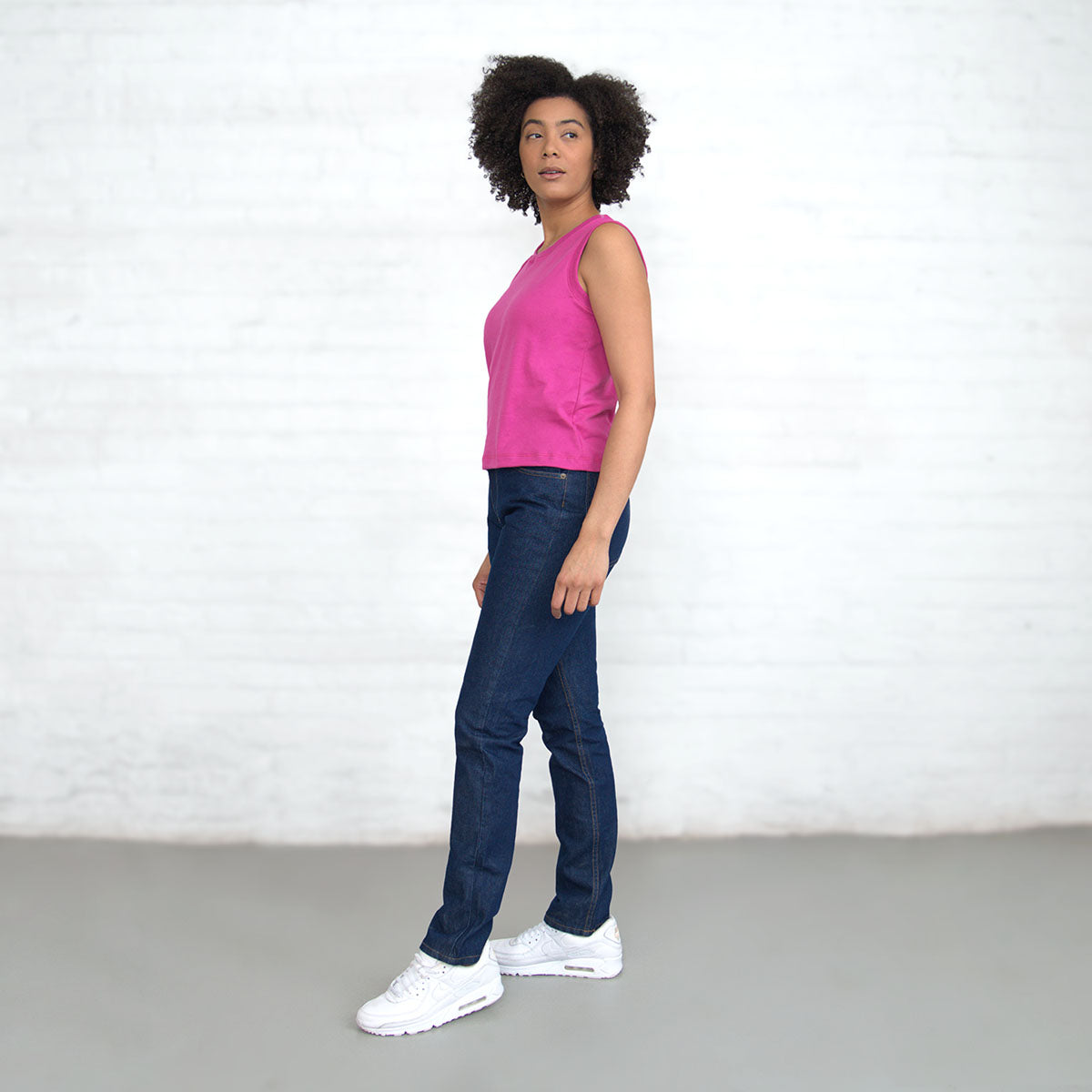 Magenta sleeveless crop top worn with jeans, side view