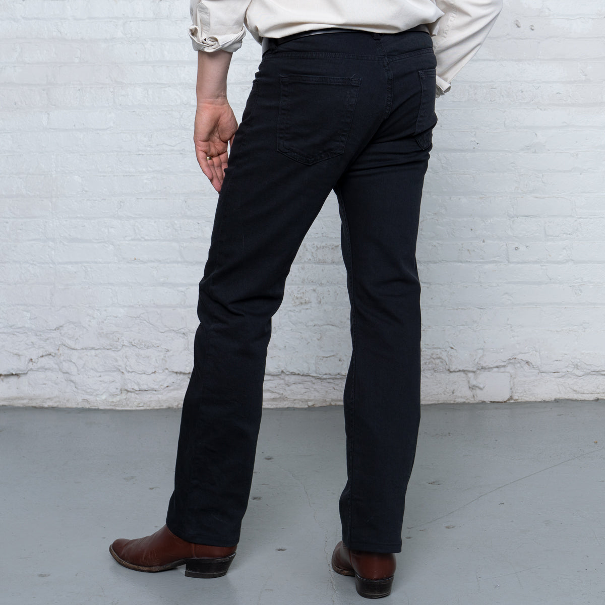 Man wearing black boot cut jeans over boots