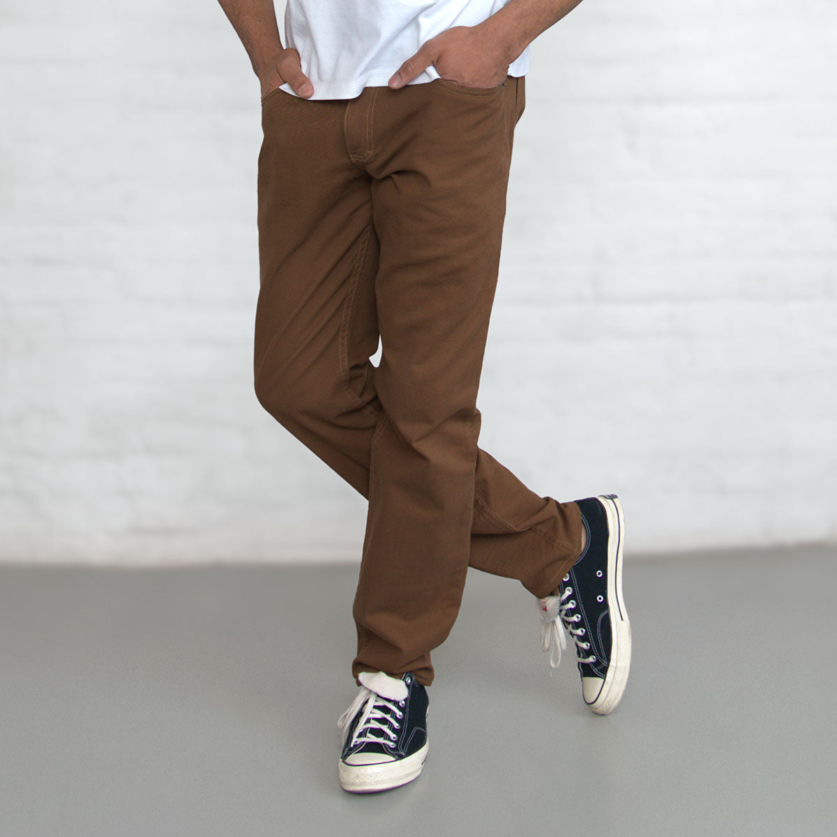 Belt loops and waistband detail on brown jeans