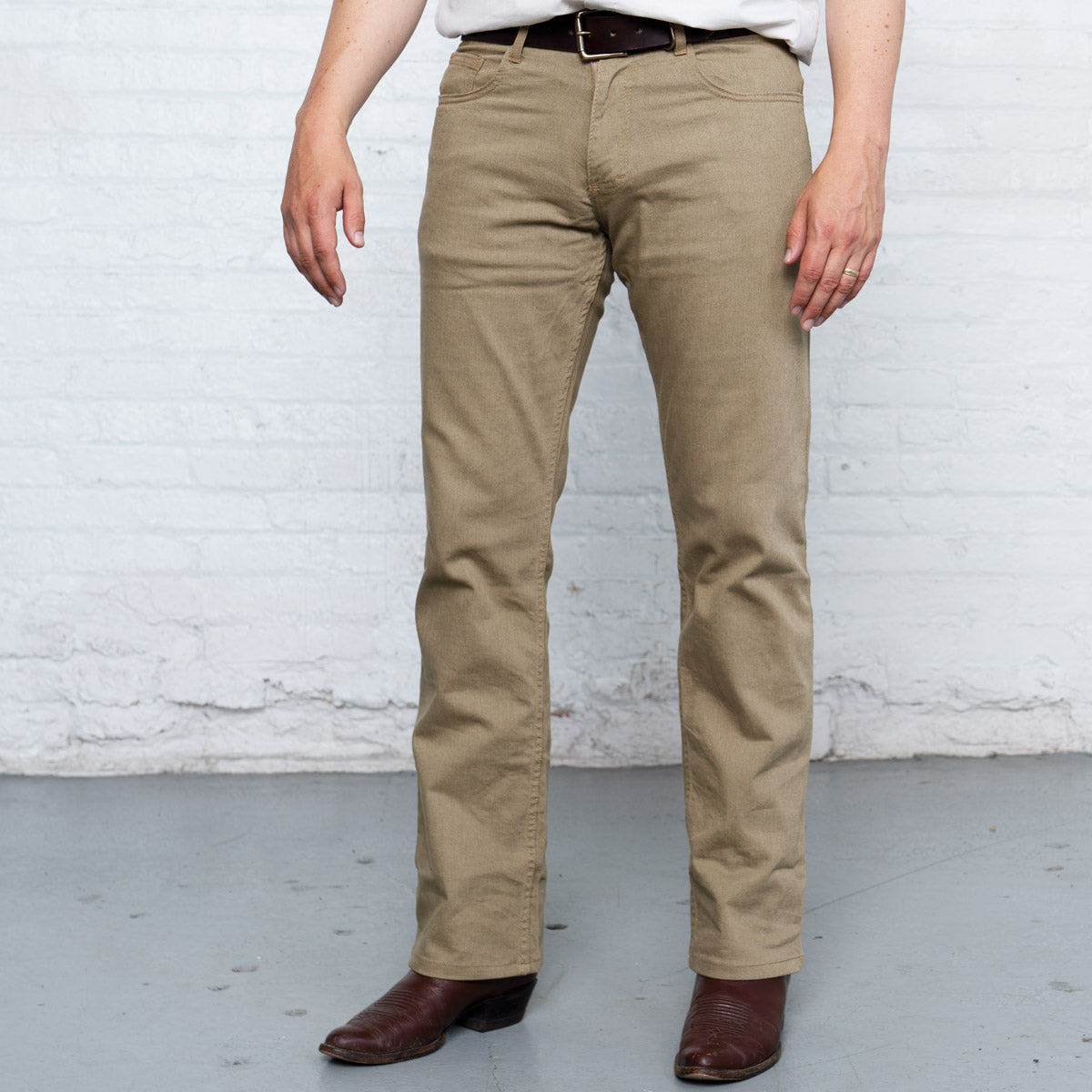 Lower leg of the khaki boot cut jeans showing the wider leg opening over a boot.