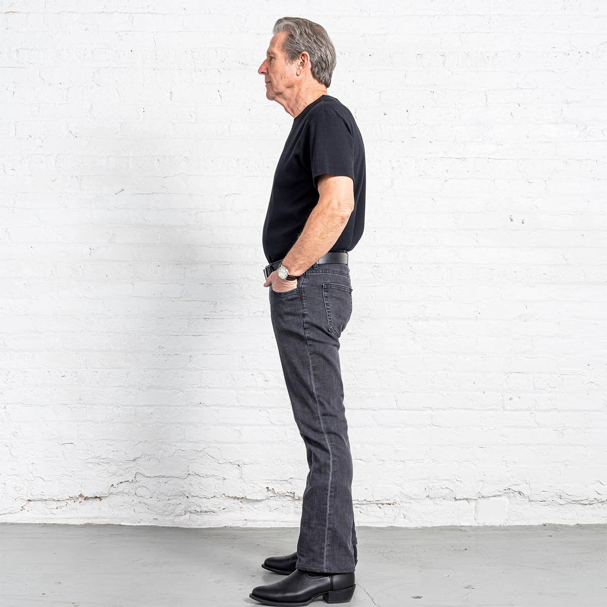 Leg opening of the grey wash boot cut jeans worn over a boot