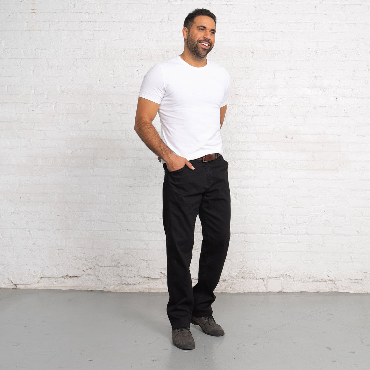 Man wearing black relaxed fit jeans, full-length front view.