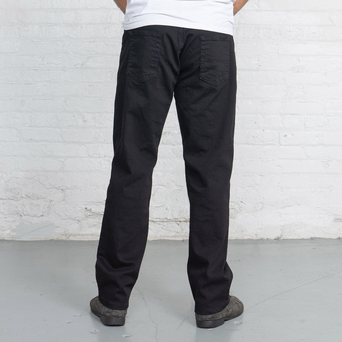 Cuff and leg opening of black relaxed fit jeans hemmed to length.