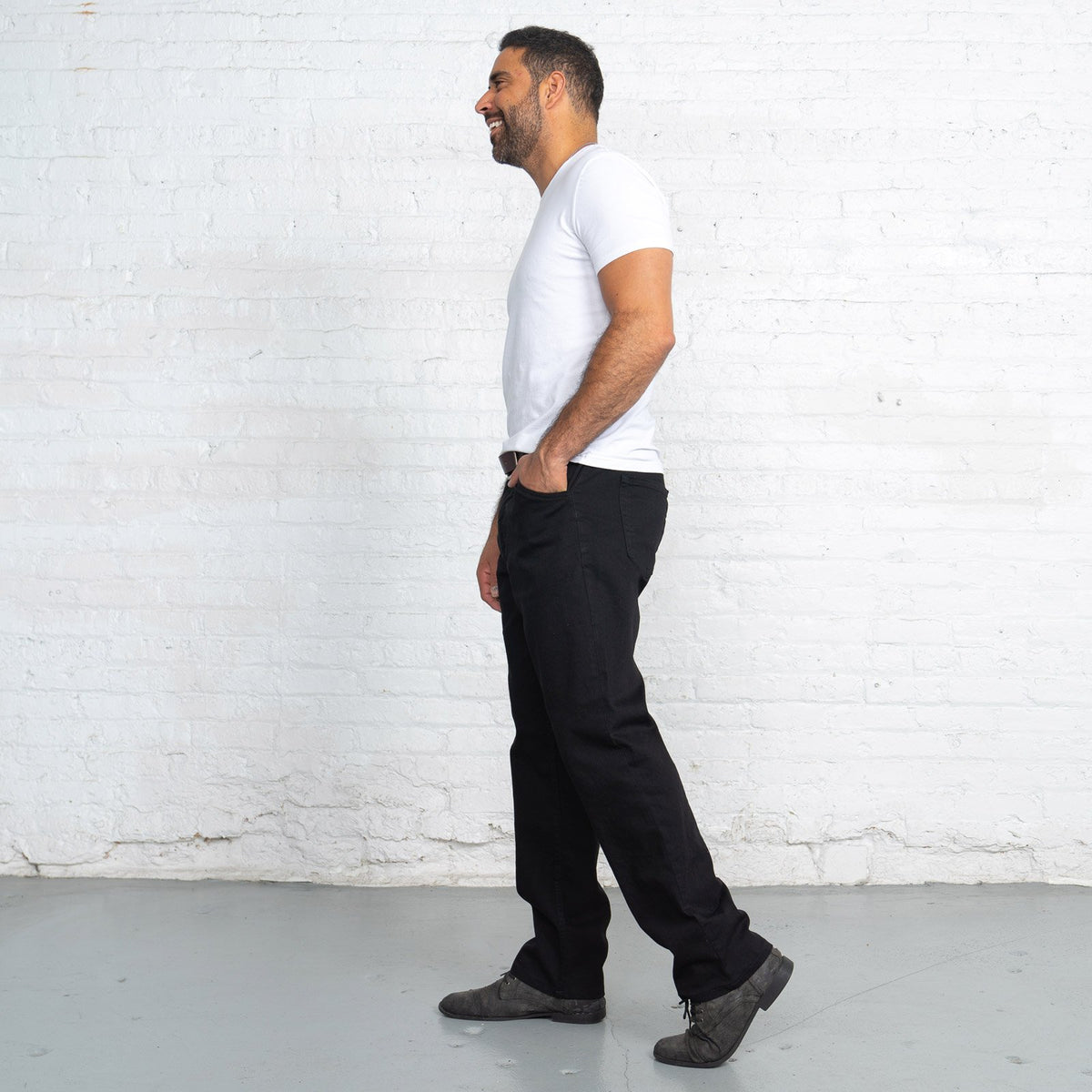 Side view of black relaxed fit jeans showing the room through the seat and thigh.