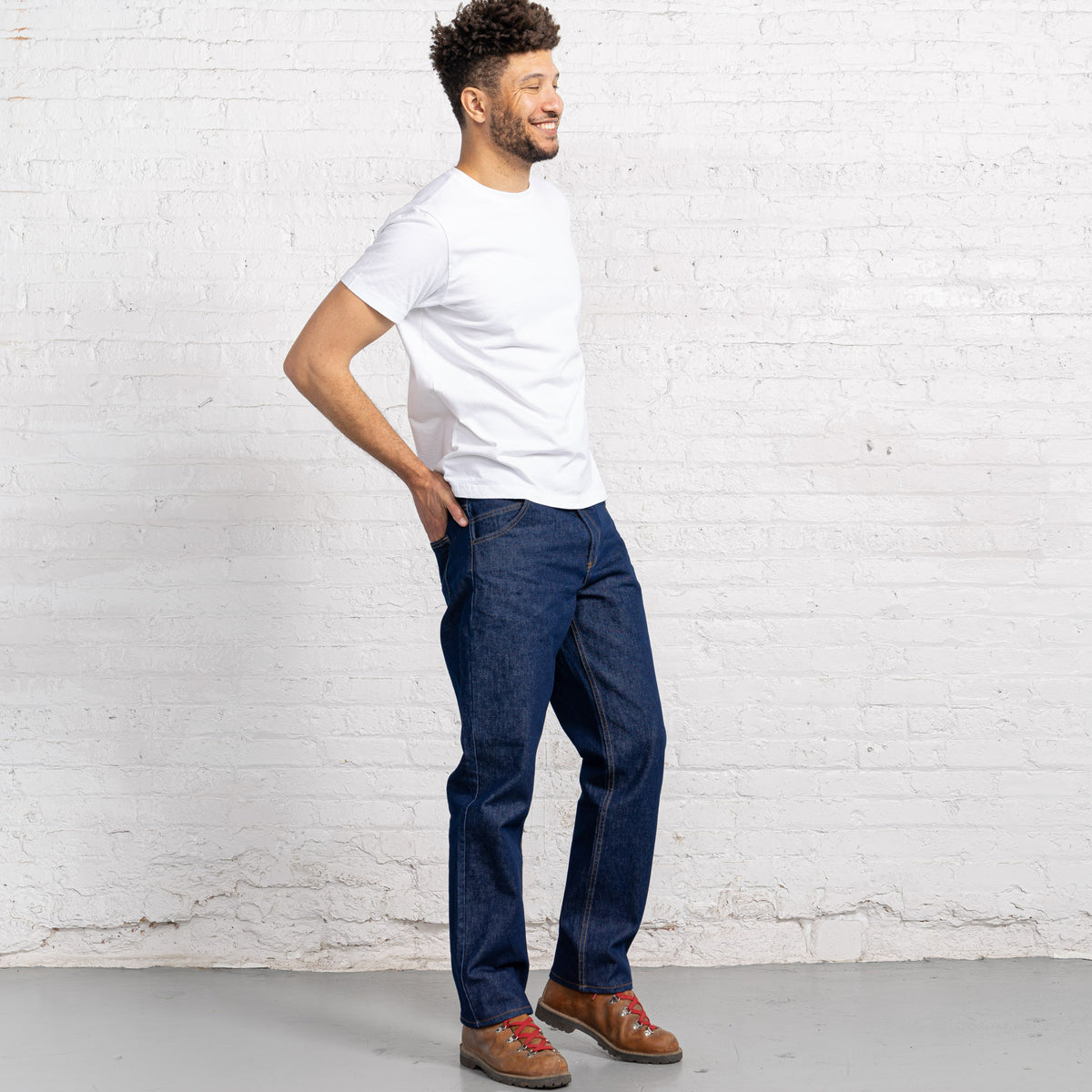 Side view of relaxed fit dark wash jeans showing medium rise and room through the seat and thigh.