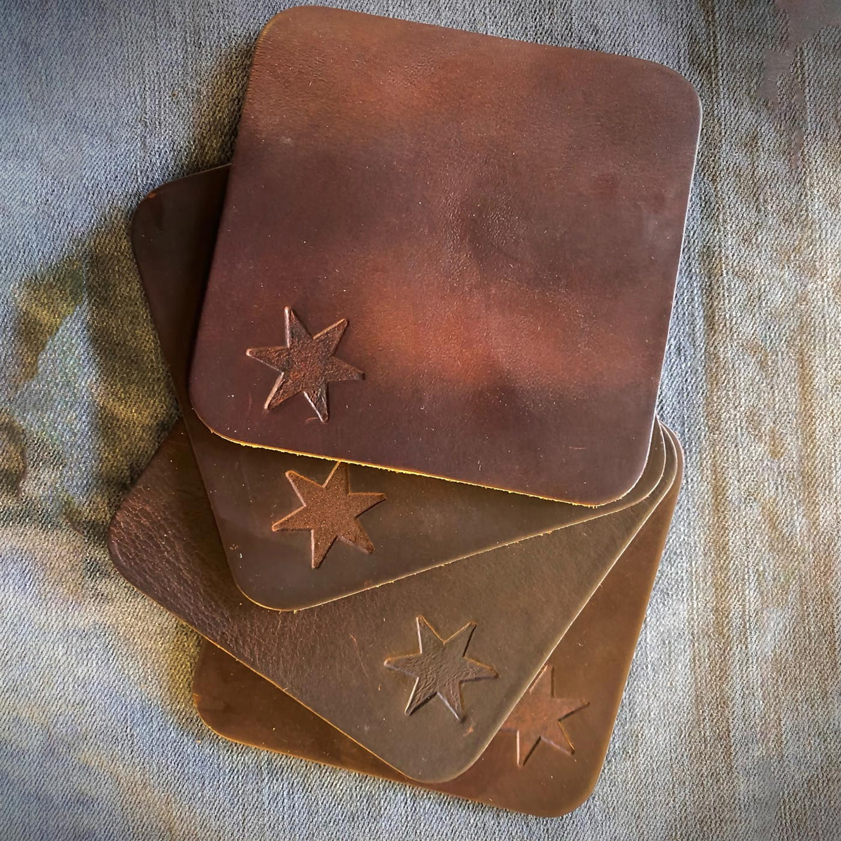 Four upcycled leather coasters with rounded edges, stacked and fanned to show the cut edge.