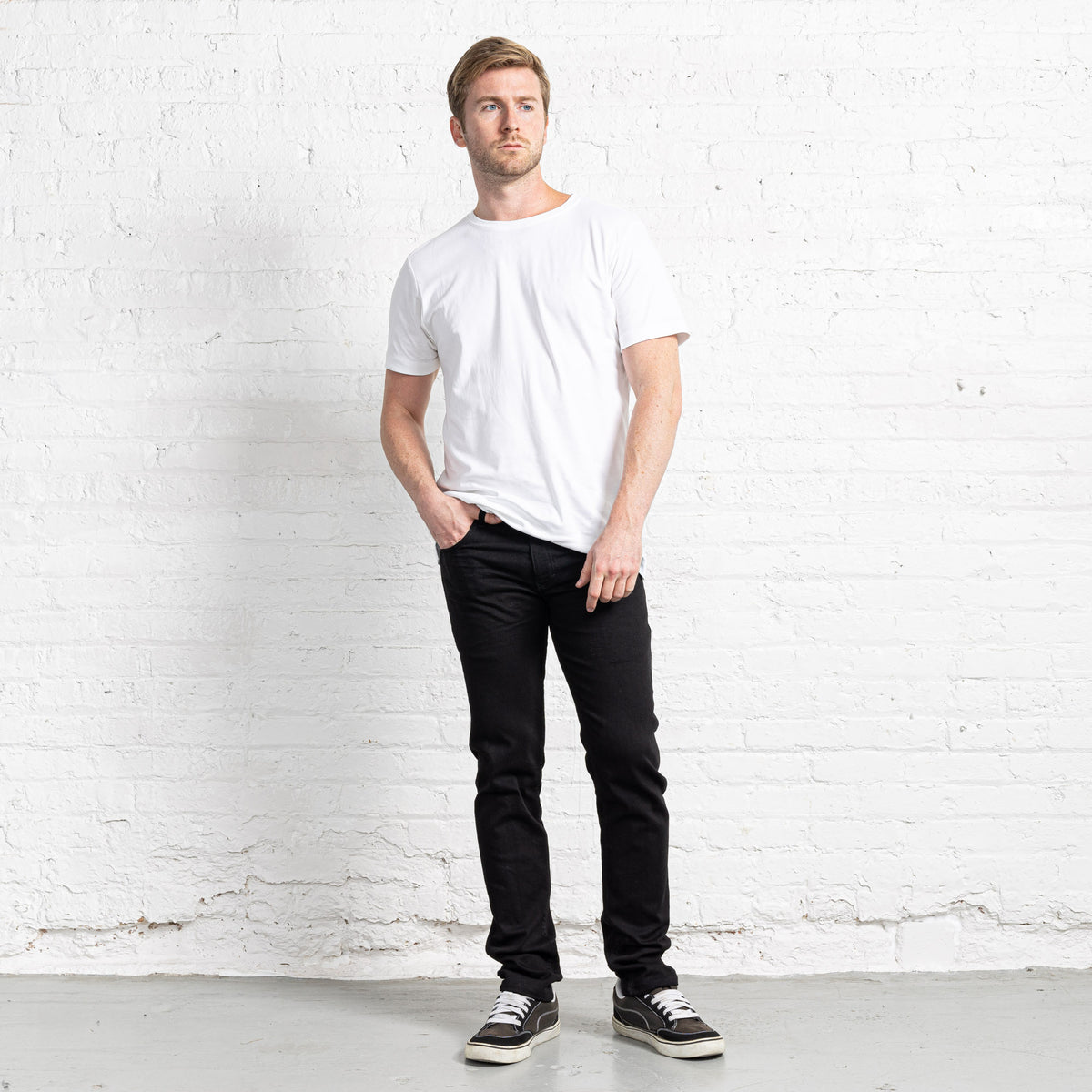 Slim fit black stretch jeans shown front on, with tapered leg below the knee