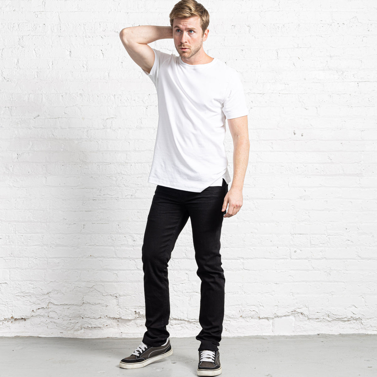 Back view of black slim fit jeans showing rear pockets and Horween leather patch at the waistband