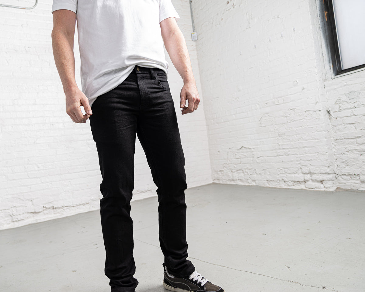Man wearing black slim fit jeans, full length view showing rise and leg taper