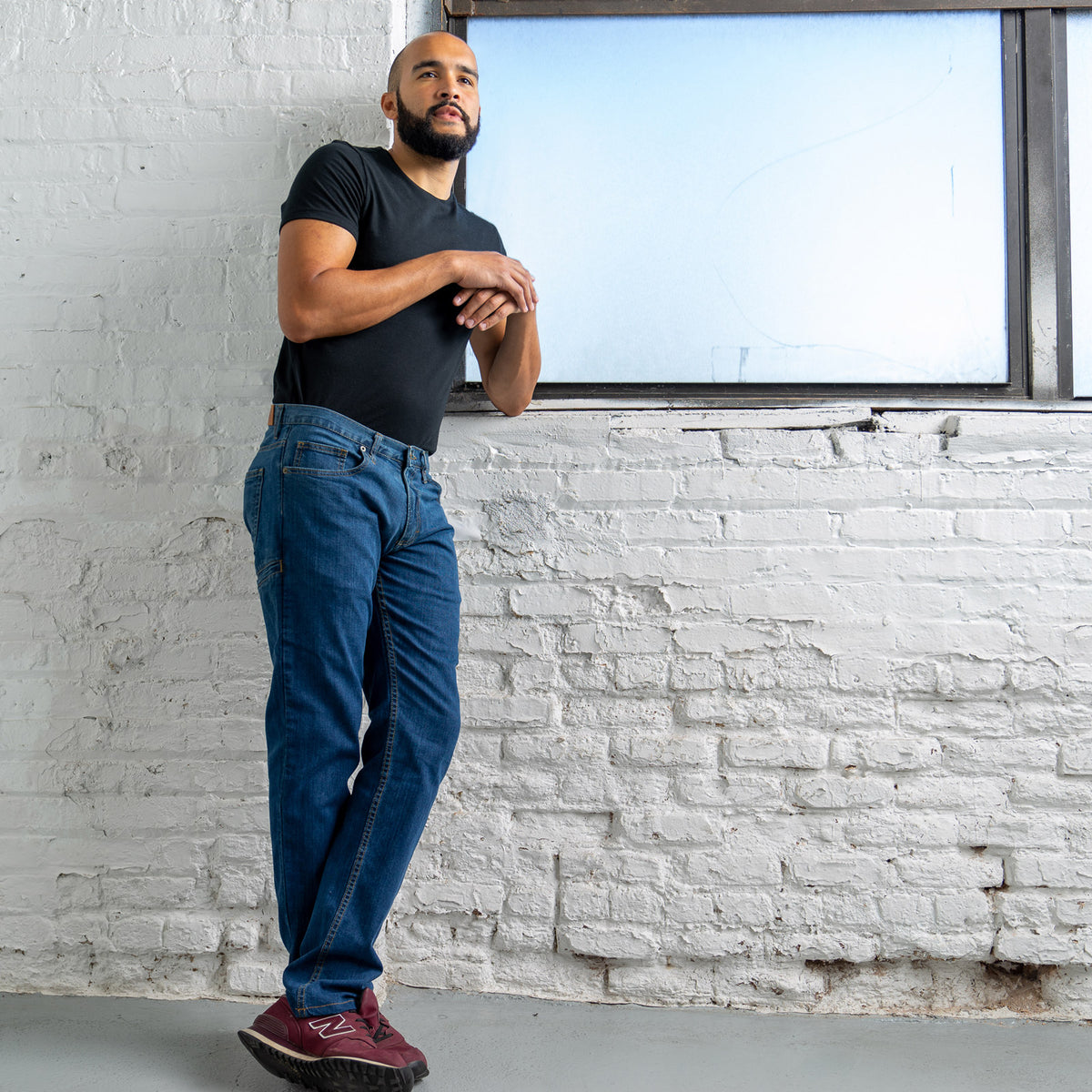Full-length view of a man wearing Tailored Fit medium wash six pocket jeans