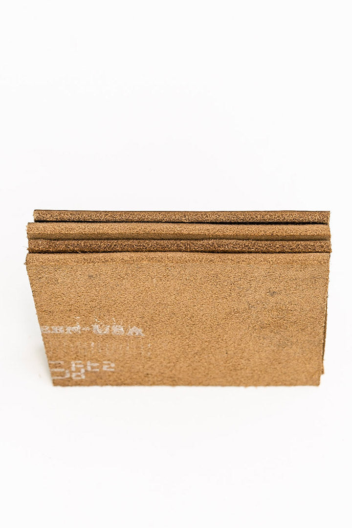 Close-up of a leather coaster edge showing thickness and rounded corner.