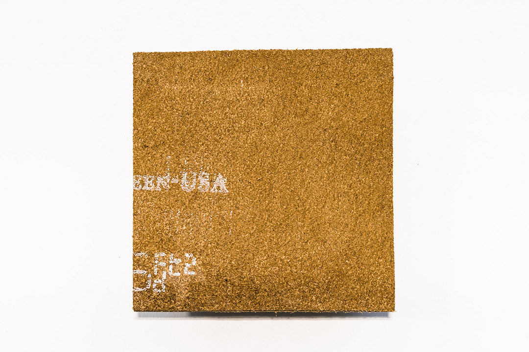 Set of four leather coasters spread apart on a table surface.